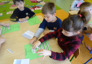 Dwoje dzieci wspólnie układa piramidę zdrowia z wykorzystaniem szablonu i napisów z produktami.